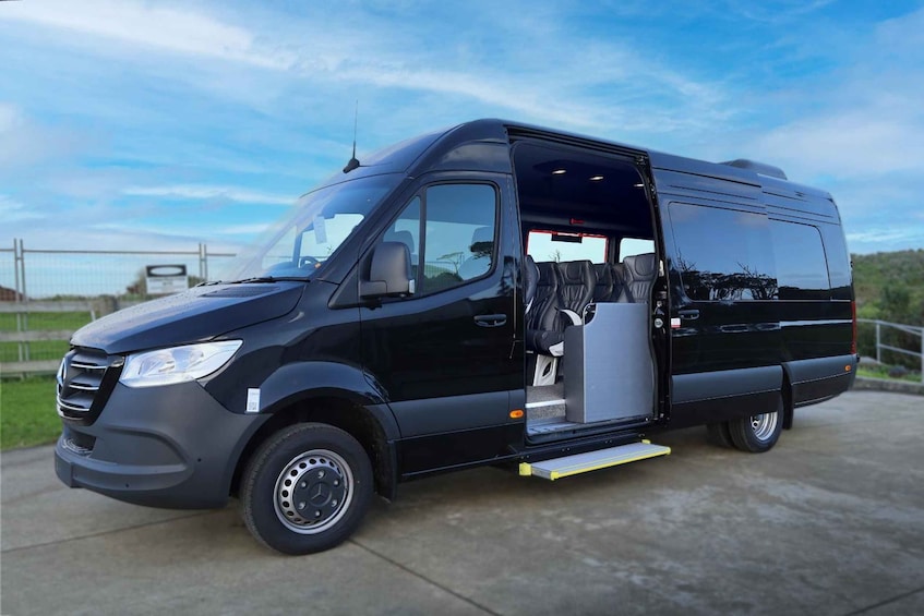 A black van with an open side door, parked on a concrete surface. 5