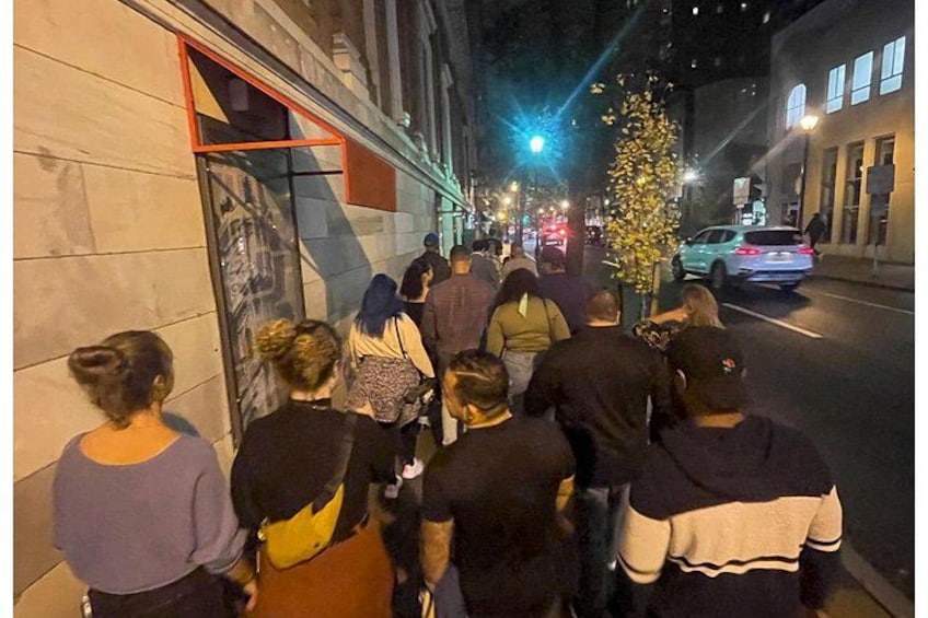 A group of people walking along a city street at night. 2
