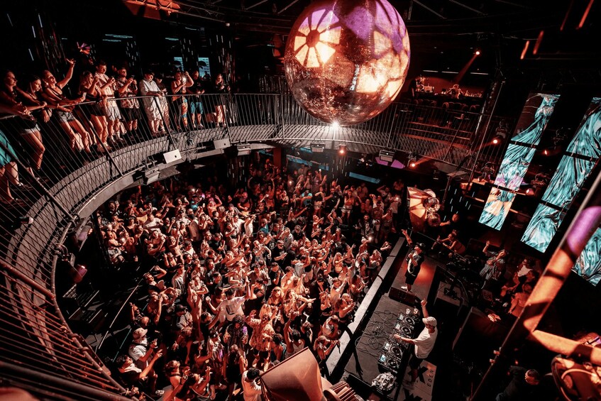 A crowded nightclub with a disco ball and a DJ booth. 5
