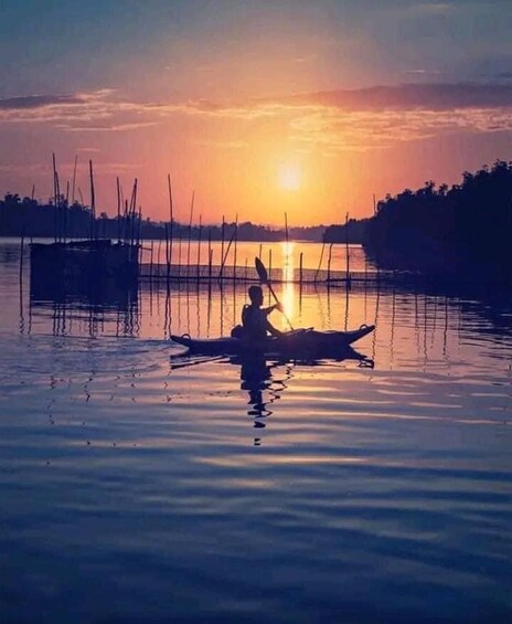 A person paddling a canoe on calm water during sunset. 2