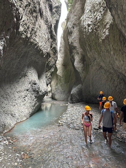 A group of people walking through a rocky canyon with a narrow stream. 4