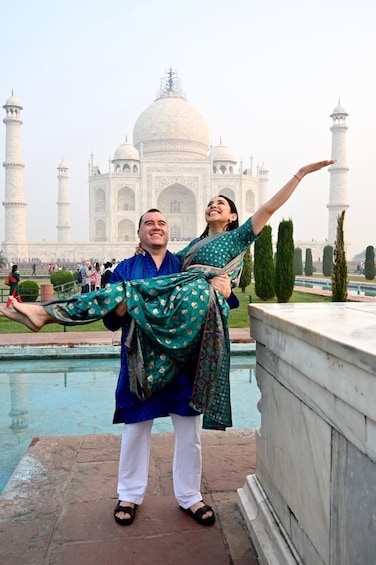 A couple posing in front of the Taj Mahal with the woman being lifted by the man. 1