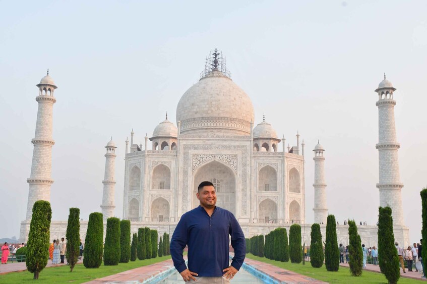 A person standing in front of the Taj Mahal with its four minarets and central dome. 2