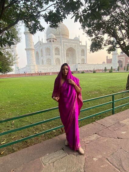 A person in a pink sari standing in front of the Taj Mahal. 3