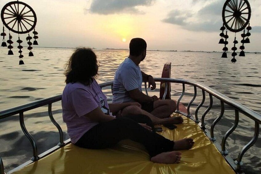 Two people sitting on a boat with a sunset in the background. 4