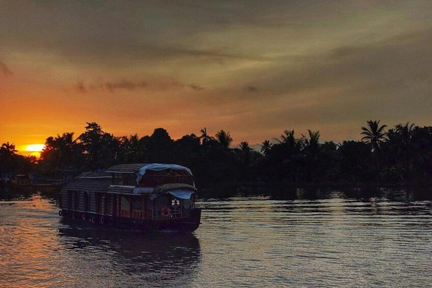 A houseboat on calm water during sunset with palm trees in the background. 1