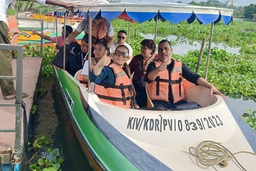 A group of people on a boat with life jackets, a river, and greenery in the background. 3