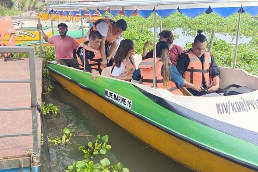 A group of people in a green and yellow boat with the text 'BLUE MARINE 16' on it, docked at a pier. 2