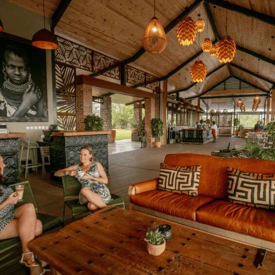 An indoor lounge with a wooden ceiling, patterned wall, and a sofa with patterned cushions. 2