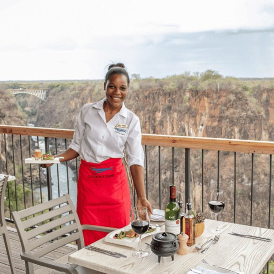 A person serving food on a balcony overlooking a canyon. 3
