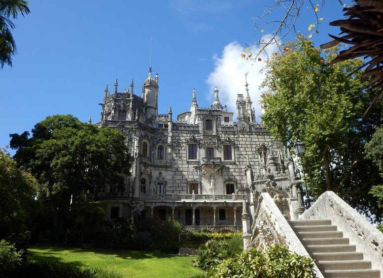 A grand, historic building with ornate architecture, surrounded by lush greenery and a stone staircase leading up to its entrance. 3