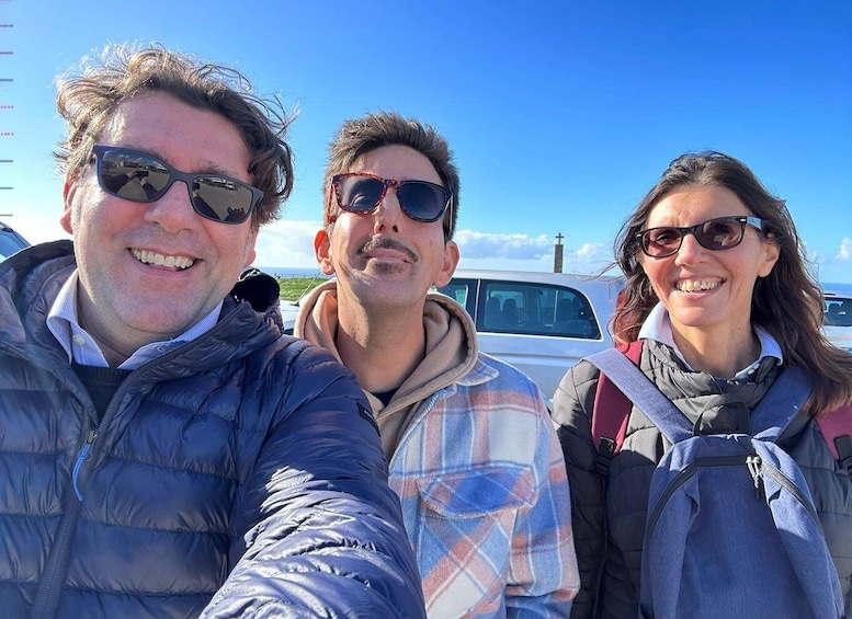 Three people taking a selfie outdoors with a clear sky and a church in the background. 2