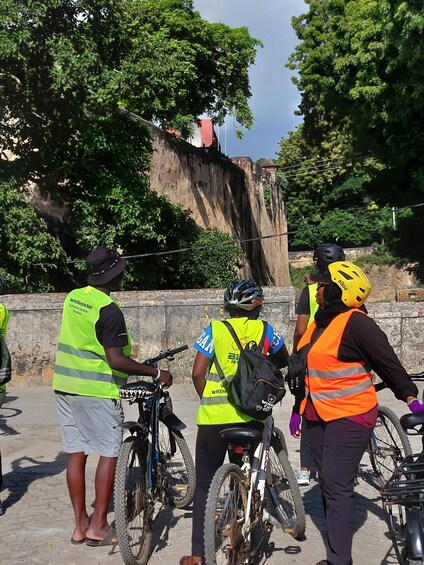 A group of people wearing safety vests and helmets, standing near bicycles. 2