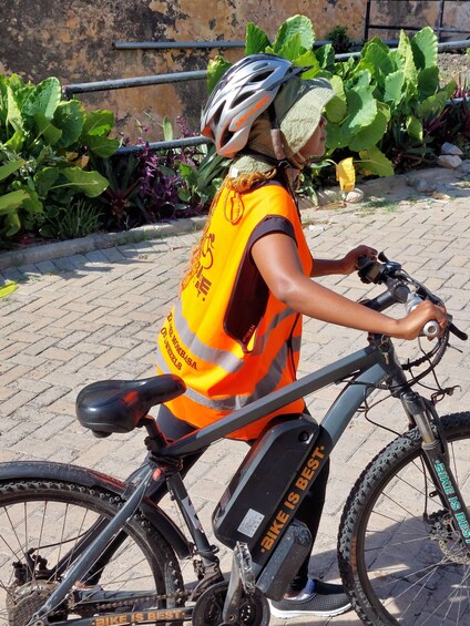 A person on a bicycle wearing a helmet and a reflective vest. 1