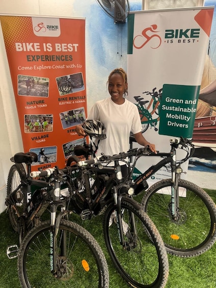 A person standing next to a display of bicycles with a backdrop advertising bike experiences and sustainable mobility. 3