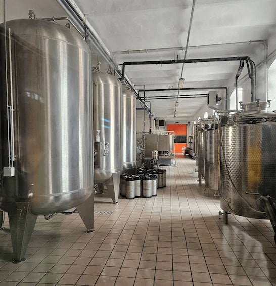 A brewery with stainless steel tanks and equipment on a tiled floor. 3
