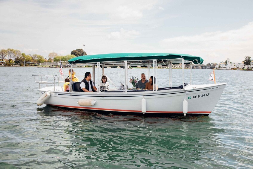 A small boat with a green canopy and a white hull, labeled CF 9384 KP, floating on calm water. 2