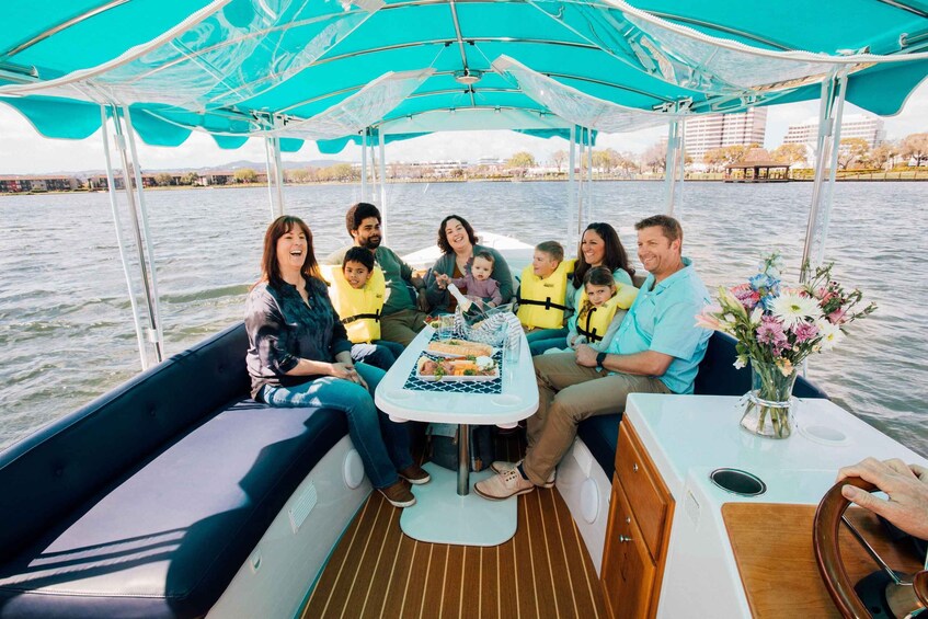 A group of people on a boat with a table and a vase of flowers. 4