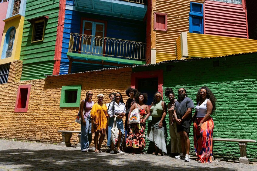 A group of people standing in front of colorful buildings with balconies. 3