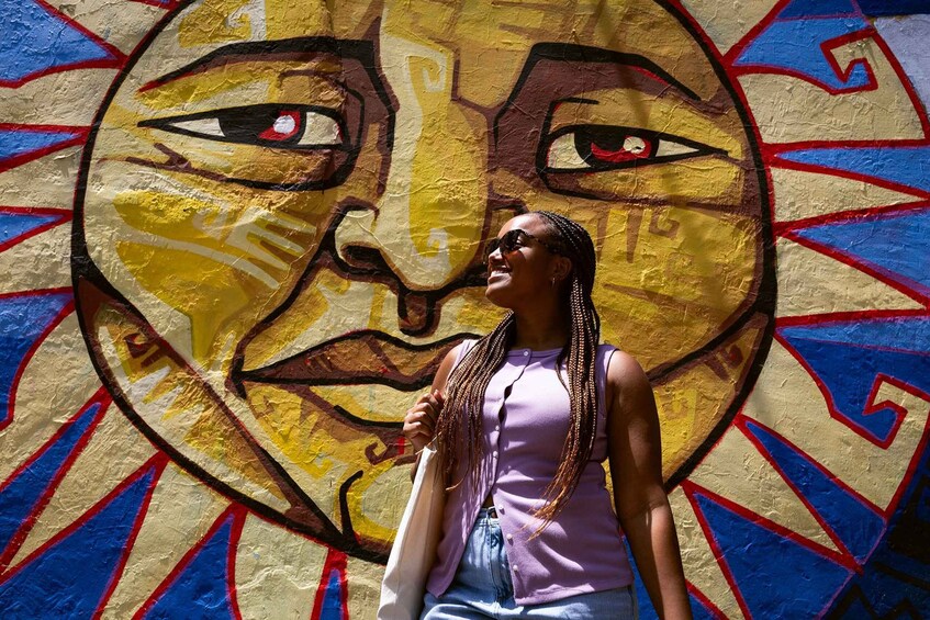 A person standing in front of a colorful mural with geometric patterns. 2