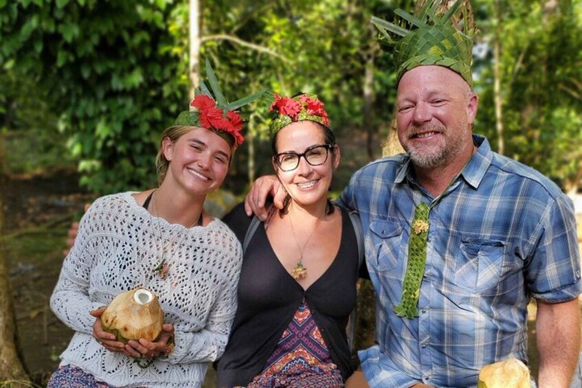 Three people outdoors, one holding a coconut. 1