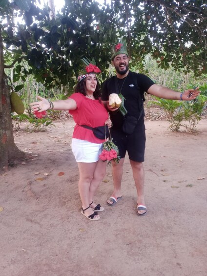 Two people standing outdoors with trees and plants in the background. 3