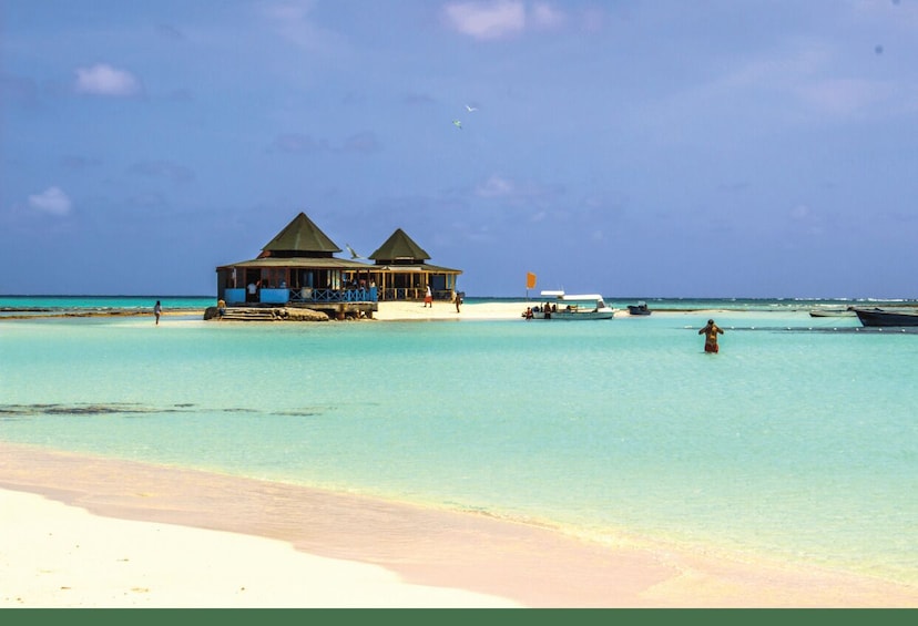 A beach with overwater bungalows and a clear blue sea. 3