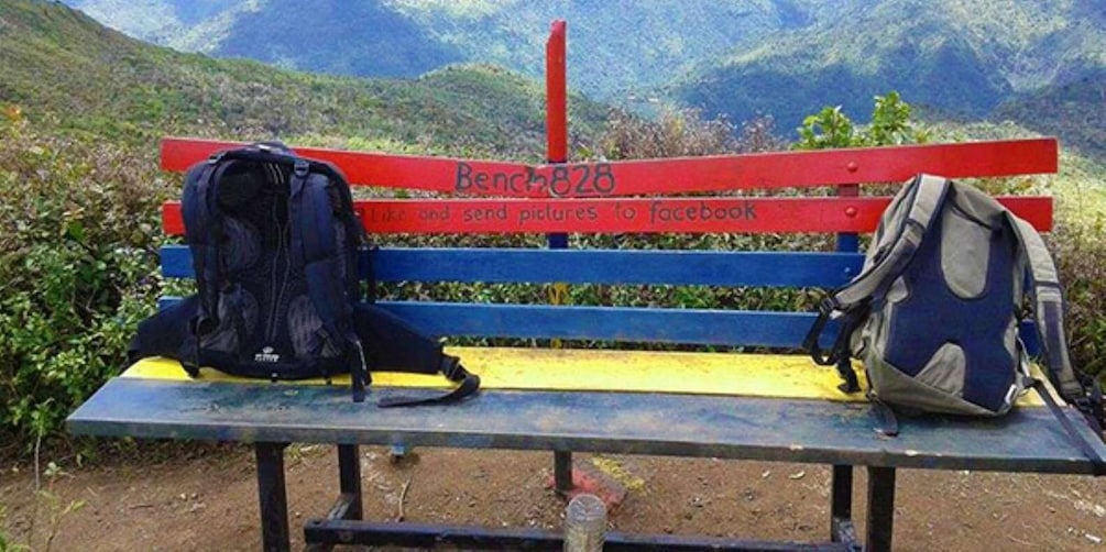 Een bank met rugzakken en een bord waarop staat: "Bench 828" en "Vind het leuk en stuur foto's naar Facebook". 3