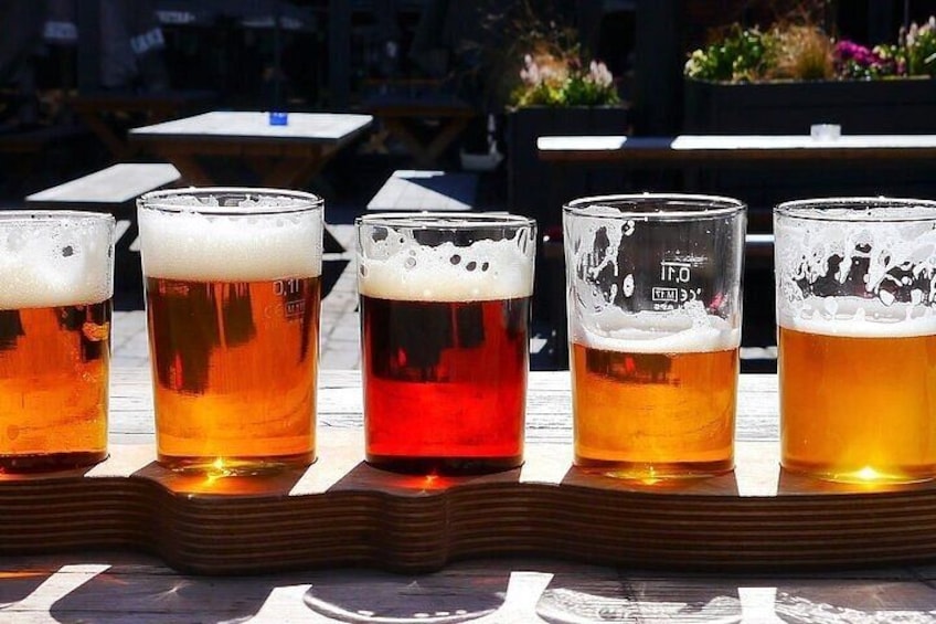 Five glasses of beer on a wooden tray. 3