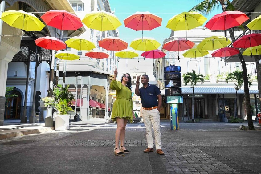 A street with colorful umbrellas, a woman in a green dress, and a man in a blue shirt. 1