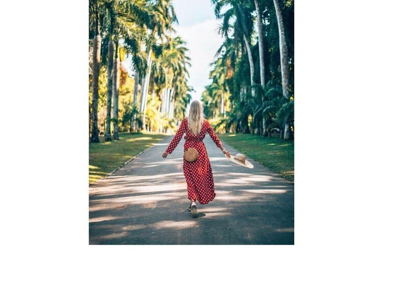 A woman in a red polka dot dress walking down a tree-lined path. 2