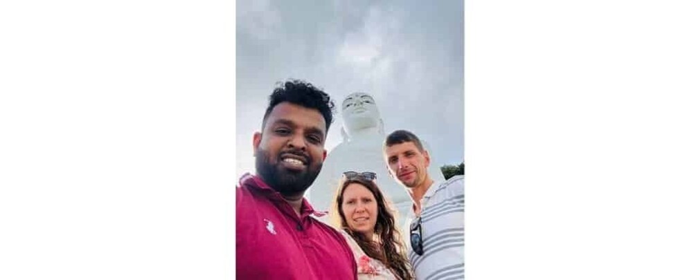 Three people standing in front of a large white statue. 4