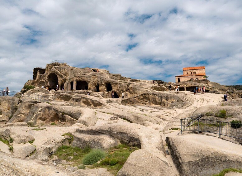A rocky landscape with ancient rock-cut architecture and a small building. 1