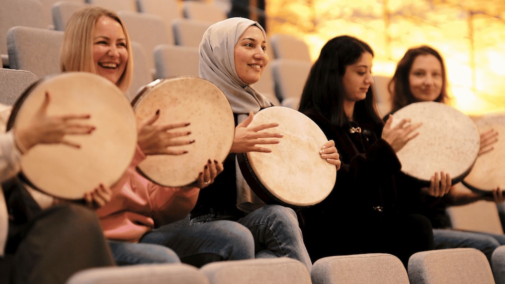 People sitting in an auditorium holding tambourines. 2