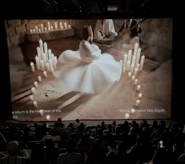 A woman in a white dress surrounded by candles in a dimly lit room. 3