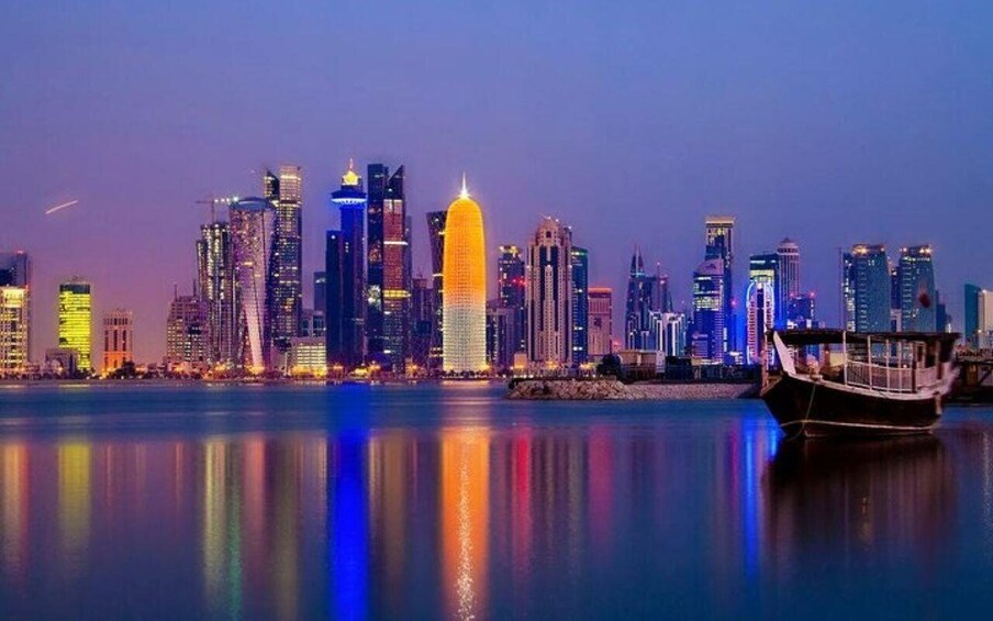 A city skyline at dusk with illuminated buildings reflecting on the water. 1