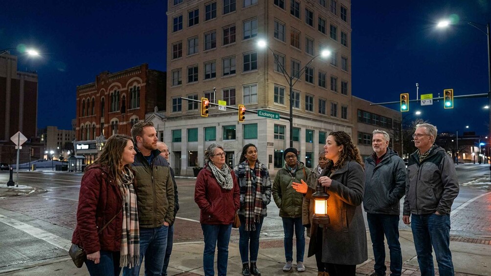 A group of people standing on a city street at night, with buildings and streetlights in the background. 3