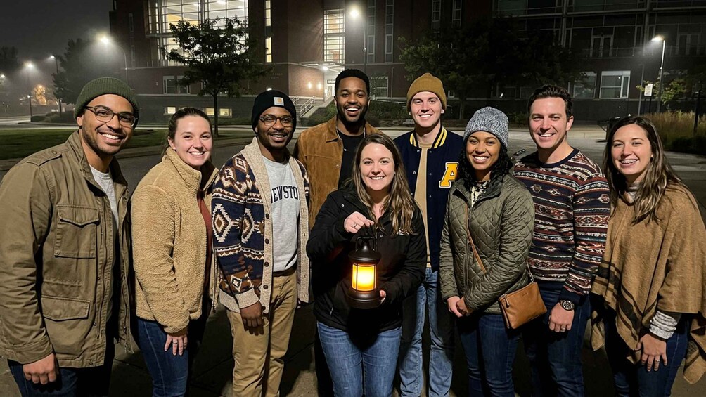 A group of people standing outdoors at night with a building in the background. 2