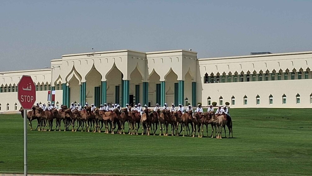 A group of riders on horses lined up in front of a large building with arched windows. 4