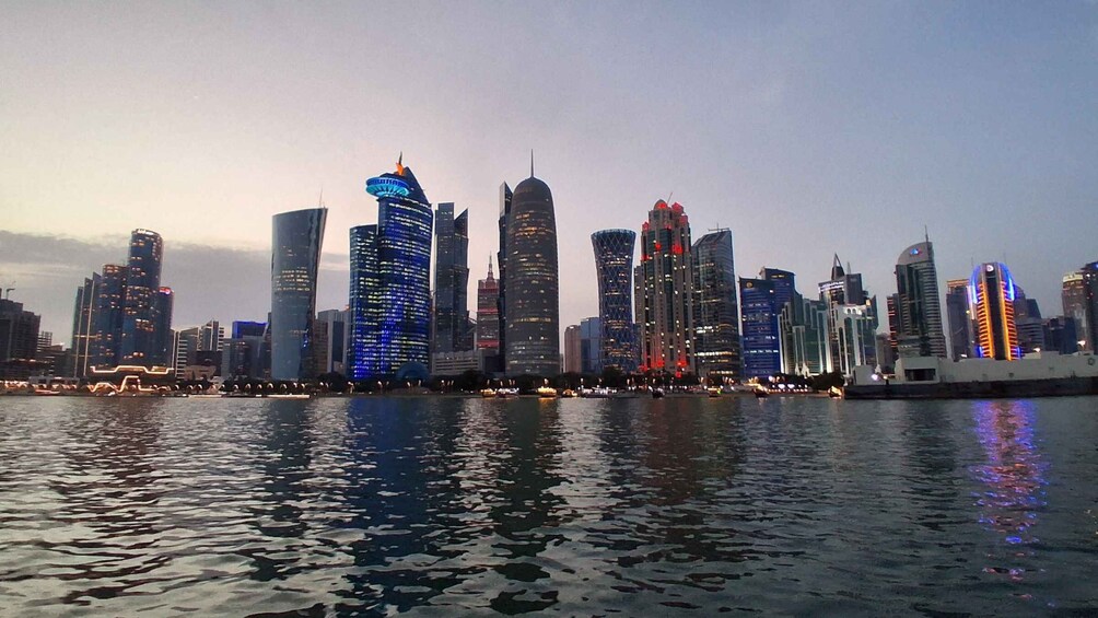 A city skyline with illuminated buildings reflecting on the water. 2