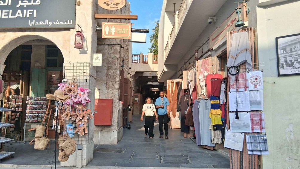 A narrow street with shops on either side, a sign for a toilet, and a sign for a place called 'CHIWEMA'. 3