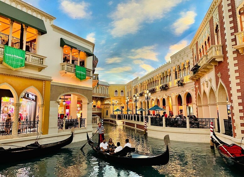 A canal with gondolas, Venetian-style buildings, and a clear sky. 1