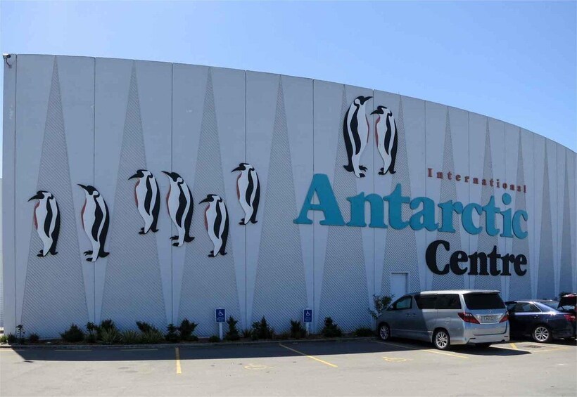 The exterior of the International Antarctic Centre with penguin murals and a parking lot. 4