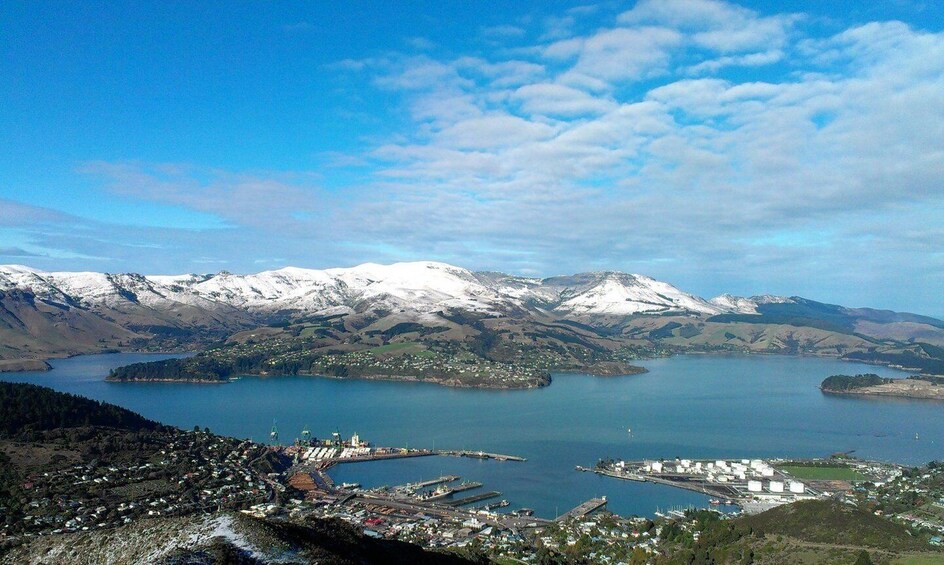 A coastal town with a harbor, snow-capped mountains, and a large body of water. 1
