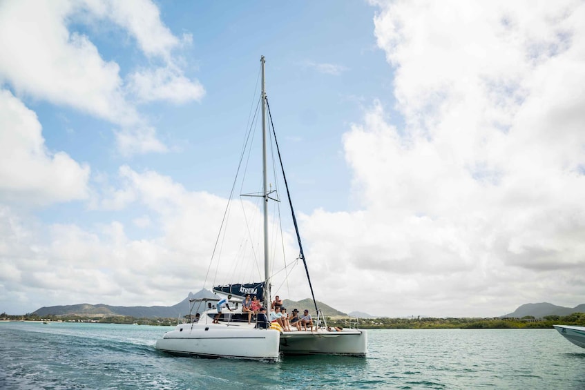 A sailboat named ATHENA on calm waters with a mountainous backdrop. 1