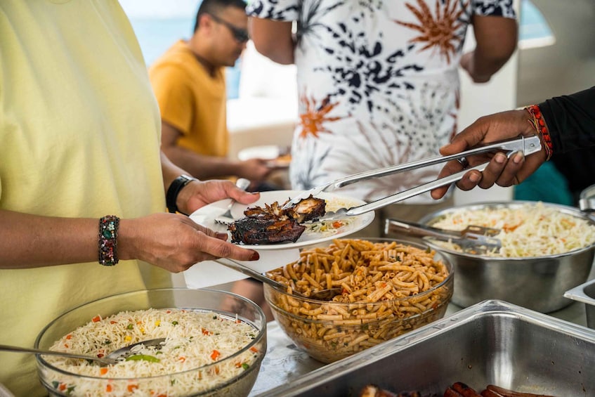 People serving themselves from a buffet with dishes like rice, pasta, and meat. 5