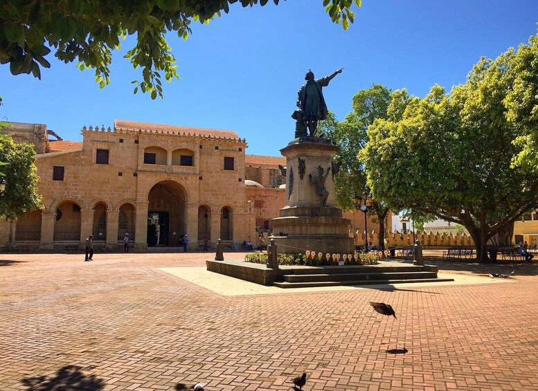 A plaza with a historic building, a statue, and a fountain. 5