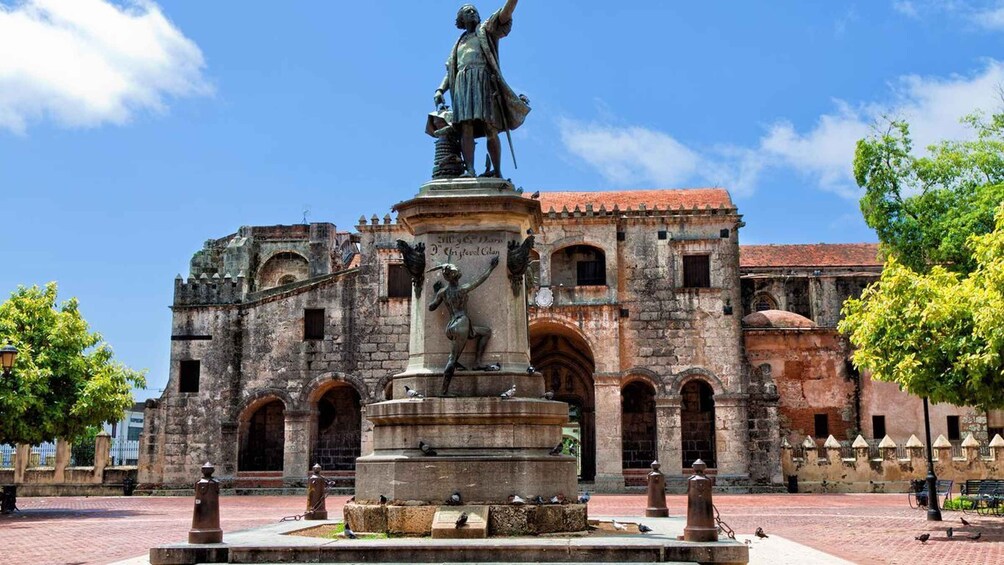 A historical building with a statue in front. 1