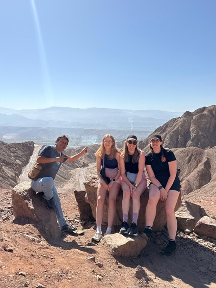 Un groupe de personnes assises sur des rochers, avec un paysage montagneux en arrière-plan. 3