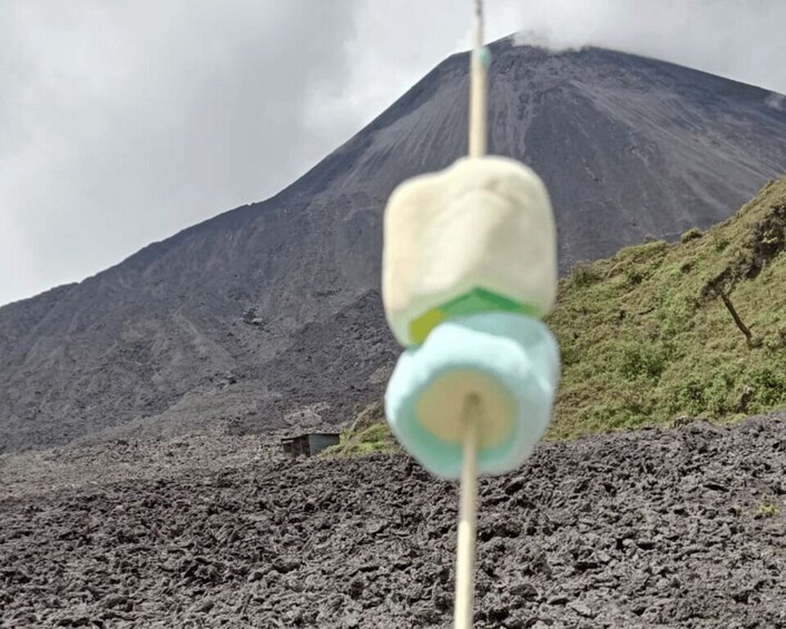 A toothpick with a marshmallow and a green object, set against a volcanic landscape. 4